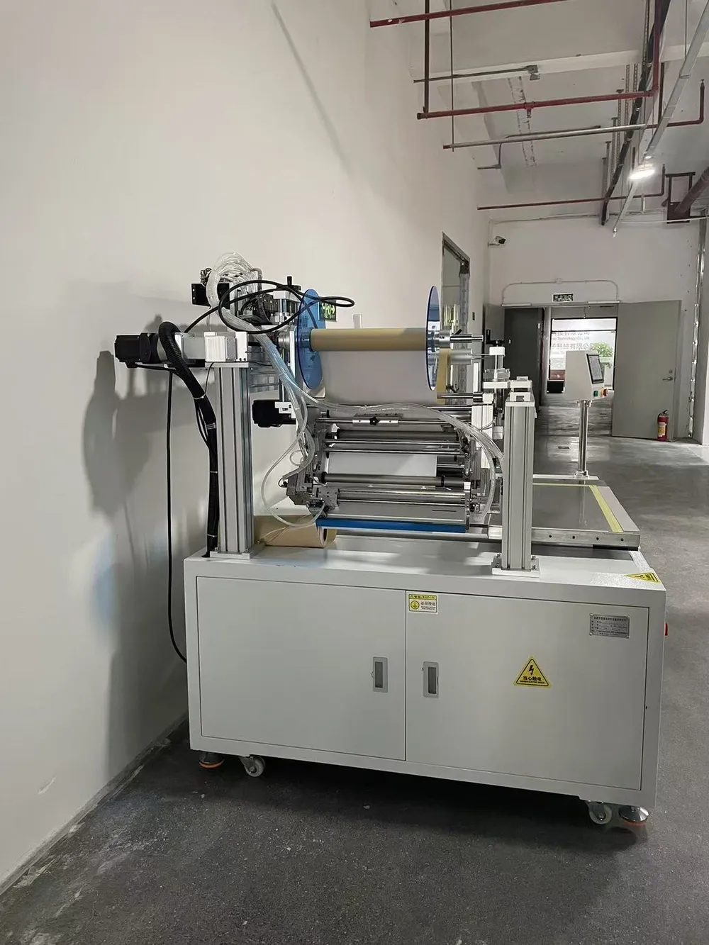 Custom Wide-Format Tape Applicator with Outfeed Conveyor — Side view: wide multi-roller head and material roll